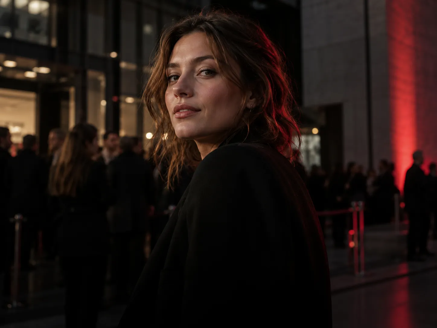 A woman in a black jacket at an evening event with red accent lighting