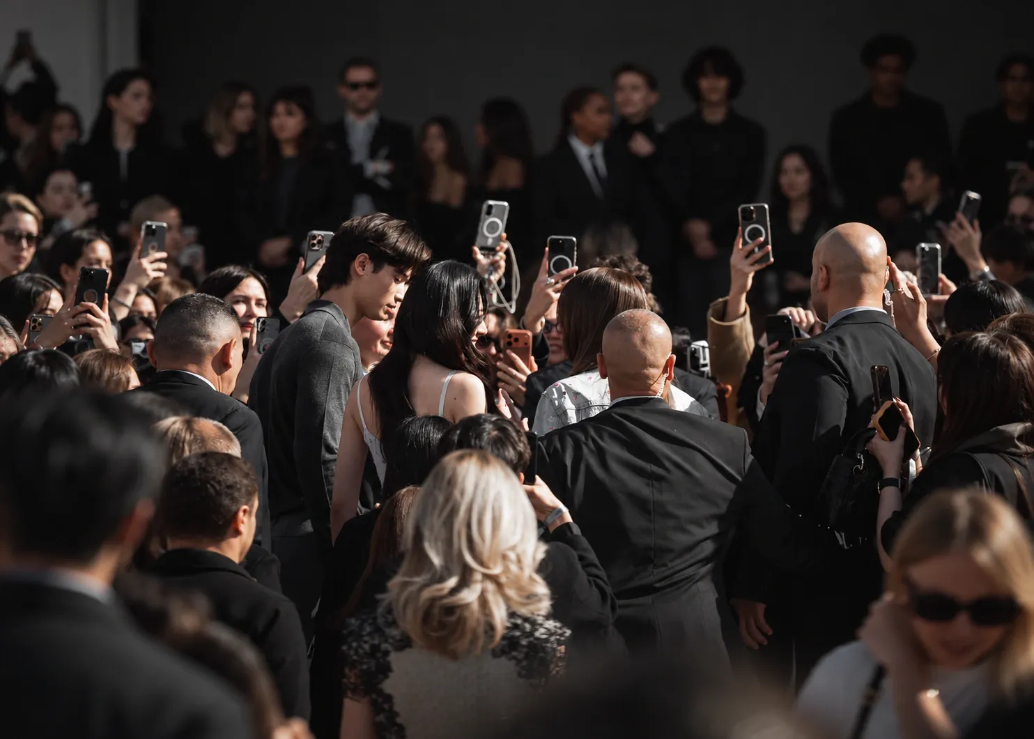 An ambassador at an event surrounded by attendees recording the moment on their phones.